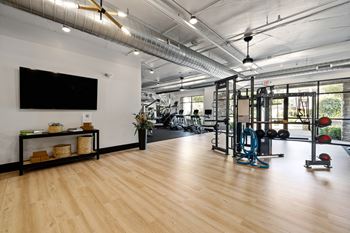 A gym with a variety of equipment including a treadmill, weights, and a television.